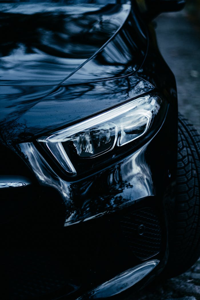 Close-up of a modern car's sleek headlight at night, showcasing automotive elegance in Berlin.